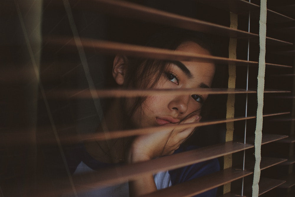 Winterdepressionen - Frau mit traurigem Gesicht am Fenster