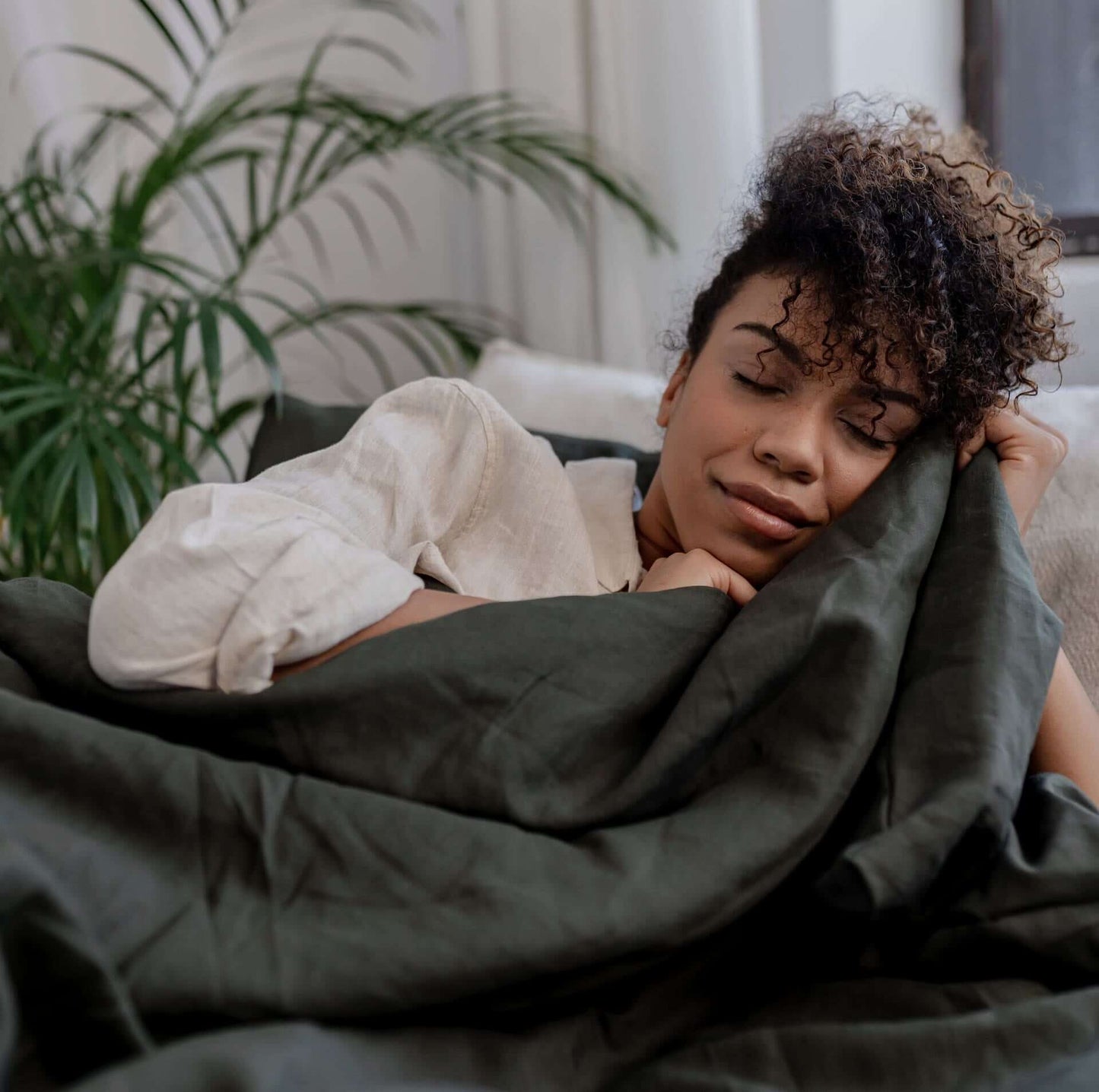 Grüner Bezug Gewichtsdecke 4 Jahreszeiten Levi von KNUS mit Model im Bett